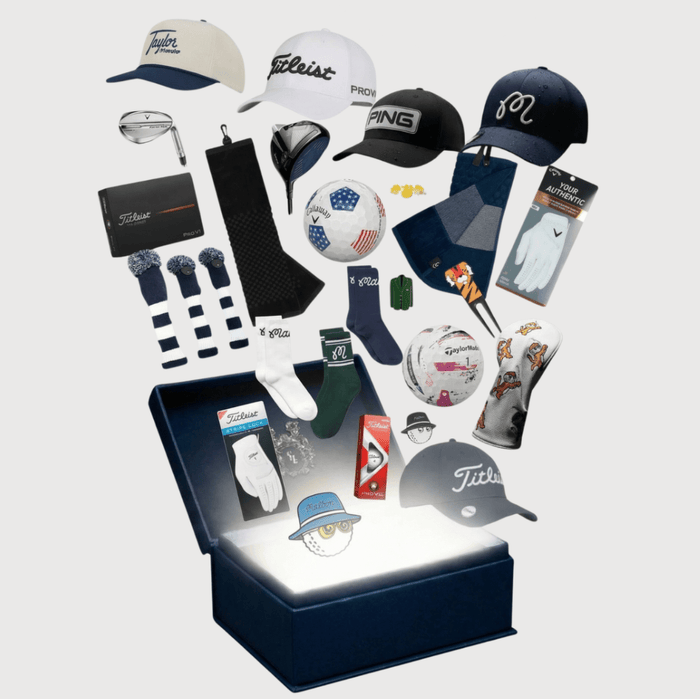 Golf caps, gloves, headcovers and golf balls bursting out of an open navy golf gift box
