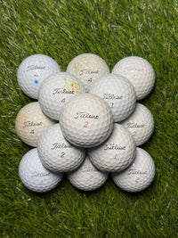 C-grade Titleist Pro V1 golf balls stacked on grass
