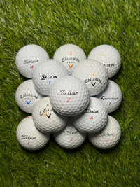 Premium brand golf ball mix in B grade stacked on grass