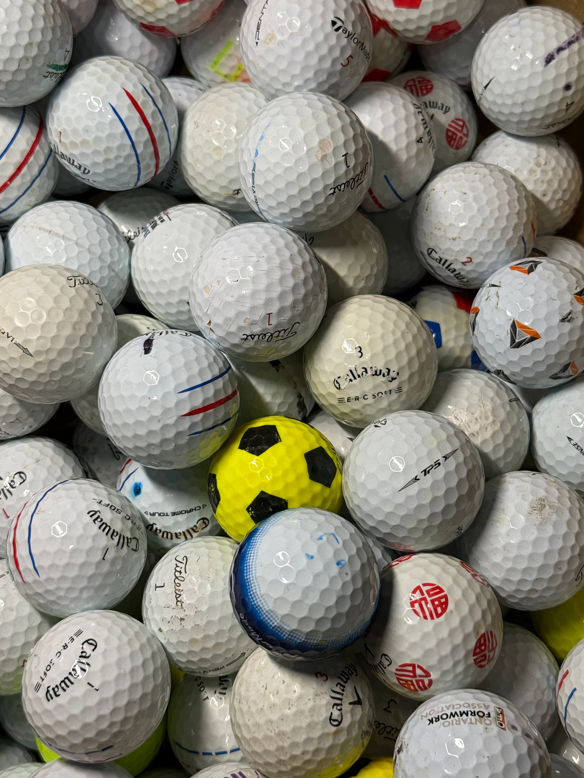 Close view of B and C grade premium golf balls including a yellow Truvis