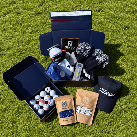 Presidential Mystery Box on grass with headcovers, a Titleist cap, glove, a dozen golf balls and tees