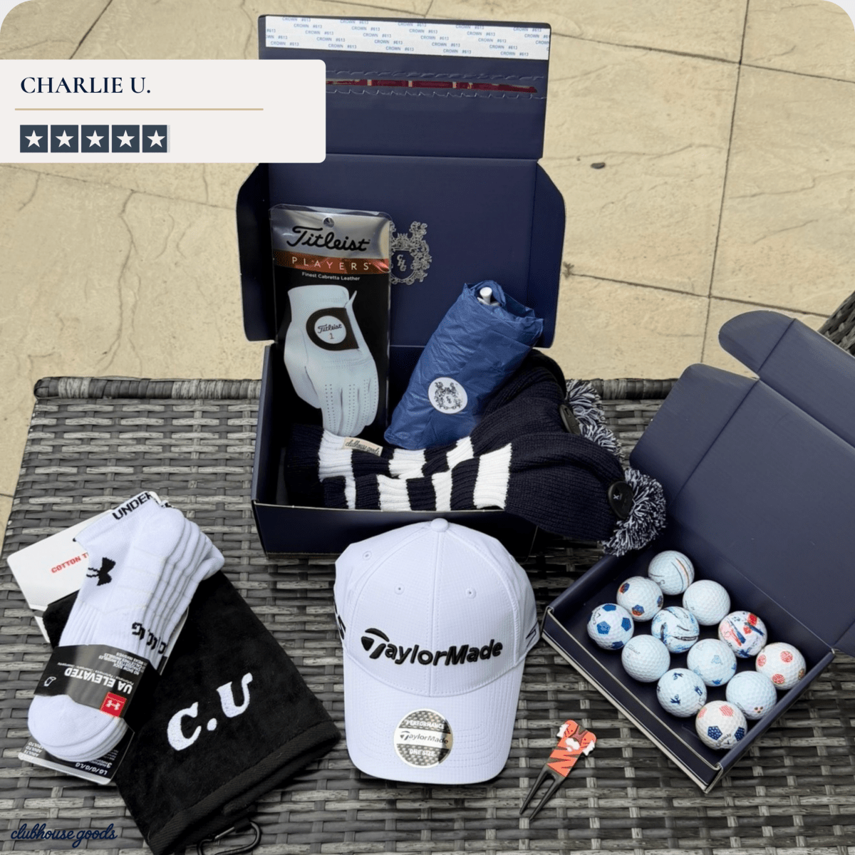 Presidential box accessories laid out on grass: a white driver headcover, golf balls, gift boxes, towel and tees